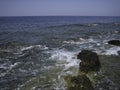 Weak waves gently wash the stones lying on the shallow bottom of the sea rocky shore in good weather