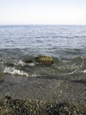 Weak waves gently wash the stones lying on the shallow bottom of the sea rocky shore in good weather