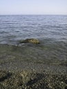 Weak waves gently wash the stones lying on the shallow bottom of the sea rocky shore in good weather