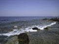 Weak waves gently wash the stones lying on the shallow bottom of the sea rocky shore in good weather