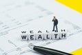 Wealth management, success investment or financial independent concept, miniature businessman standing and thinking on cube block Royalty Free Stock Photo