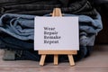 WEAR REPAIR REMAKE REPEAT text on paper note on Jeans clothes assortment Second hand sustainable shopping. Capsule