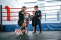 Wearing blue hand wraps. Young tattooed coach teaching the kids boxing techniques