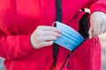 Wearing medical mask in public places concept. Cropped close up photo of young girl taking medical mask to use