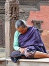 Weary old woman sleeping against carved post in square Bhaktapur Nepal Royalty Free Stock Photo