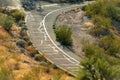 Weather beaten road in the hot summer months in Arizona with visible roadside trees and shrubs with signs Royalty Free Stock Photo