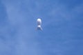 A weather blimp floats in the blue sky.