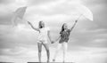 Weather changing. Girls friends with umbrellas cloudy sky background. Carefree children outdoors. Freedom and freshness