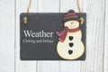 Weather closing and delays sign on a hanging chalkboard with snowman Royalty Free Stock Photo