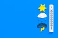 Weather forecast concept. Air temperature. Termometer among cloud and lightening, sun, rainy clouds on blue background