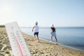 Weather thermometer and children running on sandy beach. Heat stroke warning