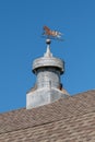 Weather vane on a red barn with brown shingled roof and  old silo on a farm. Royalty Free Stock Photo