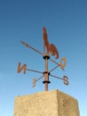Cast iron rooster wind vane under blue sky. Weather vane to indicate the direction of the wind with a wrought iron rooster and Royalty Free Stock Photo