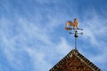 Weathercock also known as weather vane or wind vane on top of old red brick construction against a blue sky