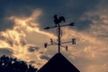 Weathercock on roof with cloudy sky