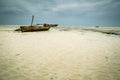 Weathered wooden fishing boat on white sand beach in Zanzibar