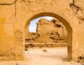 Weathered Adobe Wall with Arched Opening in Desert Landscape Under Bright Daylight Royalty Free Stock Photo