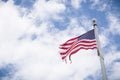 Weathered American flag on a pole with blue sky background. Old flag, flapping in the wind on pole. Fourth of July, Patriotism. Royalty Free Stock Photo