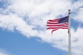 Weathered American flag on a pole with blue sky background. Old flag, flapping in the wind on pole. Fourth of July Royalty Free Stock Photo