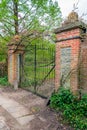 Weathered black painted iron gate between brick pillars Royalty Free Stock Photo