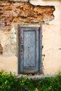 Weathered blue door with cracked paints in old city wall near abandoned palace in Busk, Western Ukraine