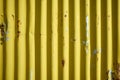 Weathered corrugated yellow rusty metal wall.