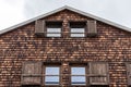 Weathered and faded wooden shingles - the facade of an alpine house. Open windows and shutters on wooden texture in shades of gray Royalty Free Stock Photo