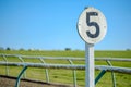 Weathered 5 furlong distance marker seen on a race course.