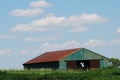 A weathered green barn with a red roof in Orland Park, IL., with a blue sky with white clouds. Royalty Free Stock Photo