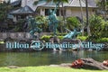 Weathered green copper statues and name sign with logo of worldwide hotel chain Hilton in Waikiki`s Hawaiian village.