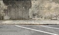 Weathered grunge concrete wall, a worn cement sidewalk and urban road. Royalty Free Stock Photo