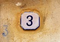 Weathered house number 3 three on old stone wall Royalty Free Stock Photo
