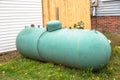 Old green propane tank in backyard of a house