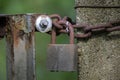 Weathered metal garden gate, closed with a rusty chain and an old padlock against a green background, copy space, selected focus Royalty Free Stock Photo