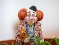 Weathered miniature garden figure of smiling clown holding a dog in plant pot