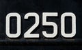 Weathered numbers zero, two, five, 0250, or 0, 2, 5 painted white on a piece of black metal. Abstarct numeral background