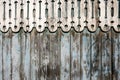 Weathered painted blue peeling wooden fence and rounded carved wooden decor on top.