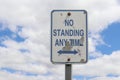 A weathered, peeling blue and white No Standing Any Time sign wi