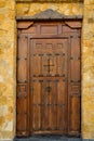 Weathered Plank Wood entrance door of residential house mansion villa with wrought-iron hinges latches. Dark brown earthy color