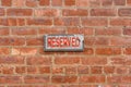 Weathered reserved sign on brick wall