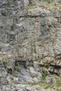 Weathered rock face texture in old stone pit with parts of green. Aged stone wall surface background pattern Royalty Free Stock Photo