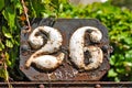 A weathered, rusty house number plaque, showing the number twenty six in a vintage font