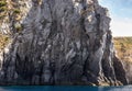 Weathered seaside rock face texture with parts of green and blue water. Aged volcanic stone wall surface background Royalty Free Stock Photo