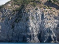 Weathered seaside rock face texture with parts of green and blue water. Aged volcanic stone wall surface background pattern Royalty Free Stock Photo