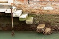 Weathered steps by the brick building wall by the canal in Venice, Italy