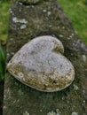 Weathered stone heart on top of gravestone