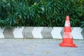 Weathered traffic cone beside concrete barrier and greenery Royalty Free Stock Photo