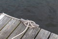 Weathered wood boat dock with wood cleat and mooring rope attached, creative copy space