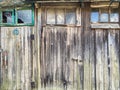 Weathered wooden barn wall. closed doors with padlocks and windows with broken glass