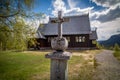 Weathered wooden cross in front of historic church in Kvikkjokk, Sweden.